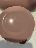 Close-up of the bottom of a pink silicone vessel, showing embossed recycling symbols on a glossy surface.