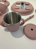 A dusty pink stainless steel tumbler with two handles, shown with its matching pink lid and straw on a white surface.