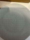 Close-up of the bottom of a light gray round product, showing embossed recycling and safety icons, on a white surface with a brown cardboard edge visible at the top.