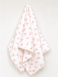 A white muslin baby blanket with a pink bow pattern and a cream scalloped edge, draped against a plain white background.